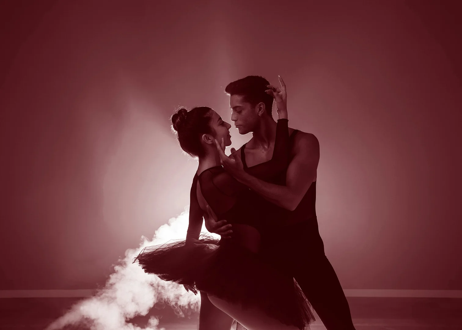 A partnered couple in a close, dipping embrace lit in deep red, illustrative of Alexei Ratmansky's musically driven neoclassical choreography
