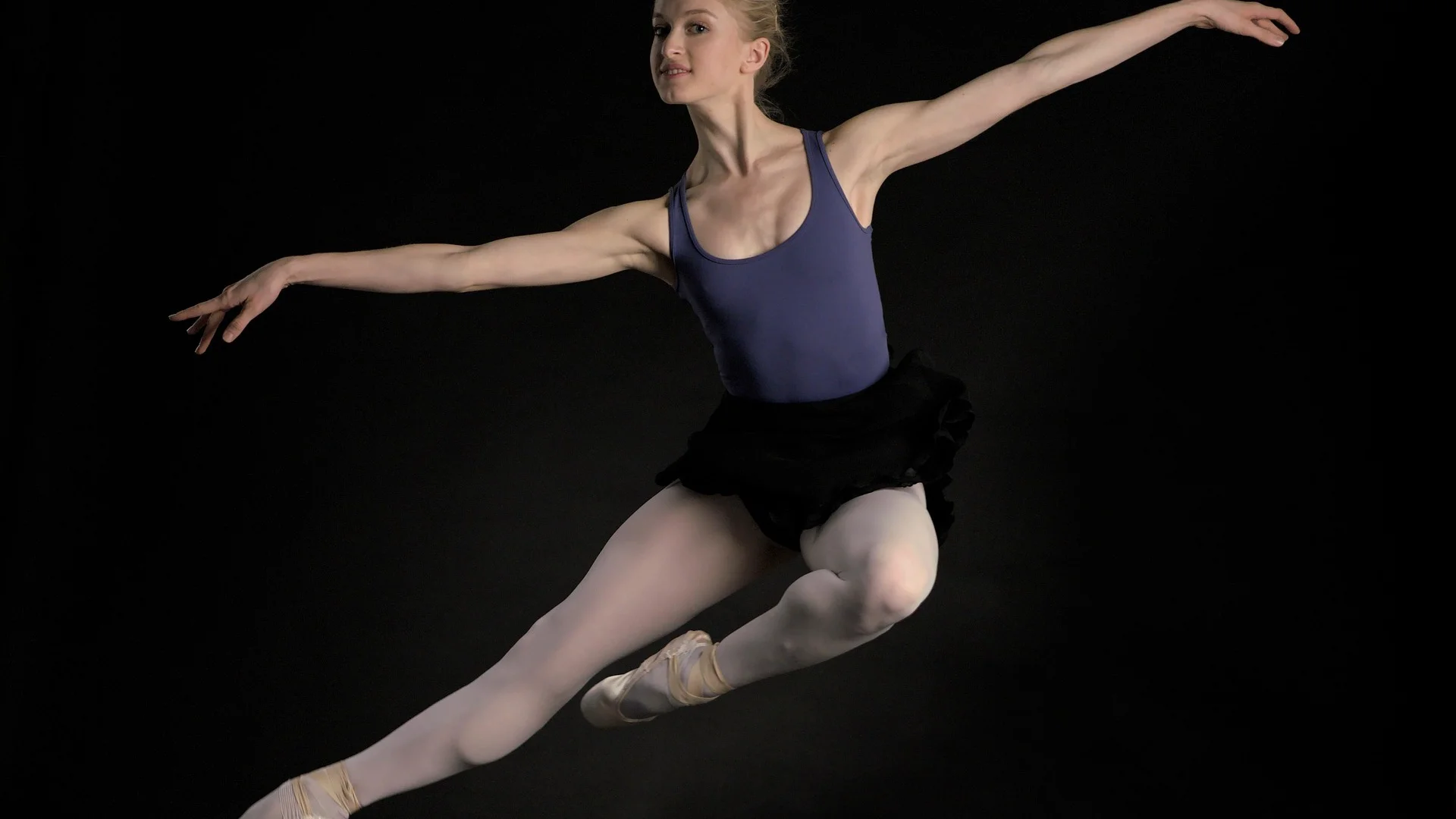 A dancer in a hyperextended pose inside a stark white box set, illustrative of Chroma