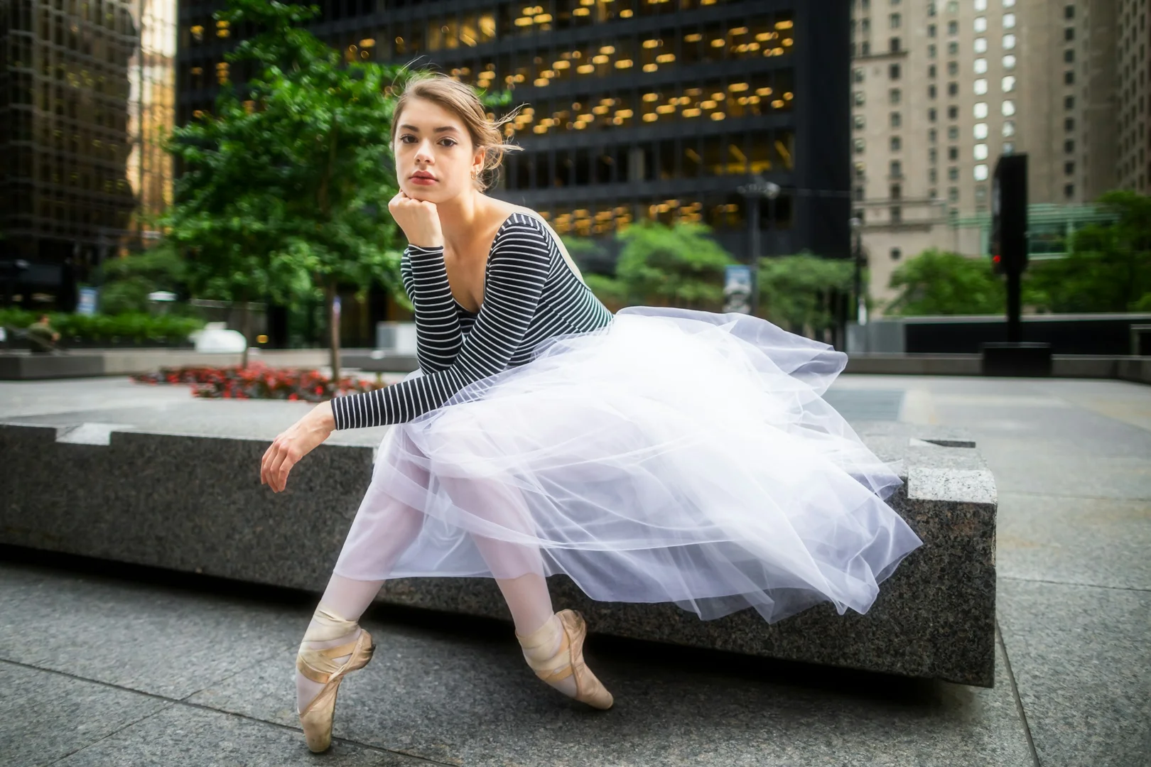 A dancer in a tutu and striped top posed starkly in an urban plaza, illustrative of Mats Ek's reimagining of Giselle
